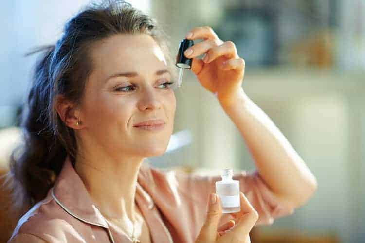 woman applying serum to her face