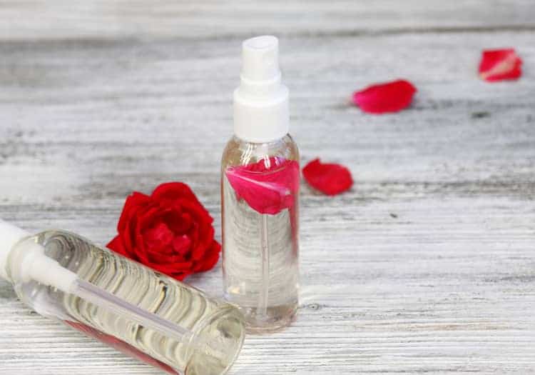 bottles of rose water surrounded by flowers