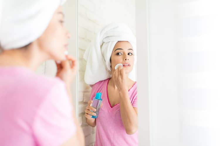 woman applying rose water or witch hazel toner to her face