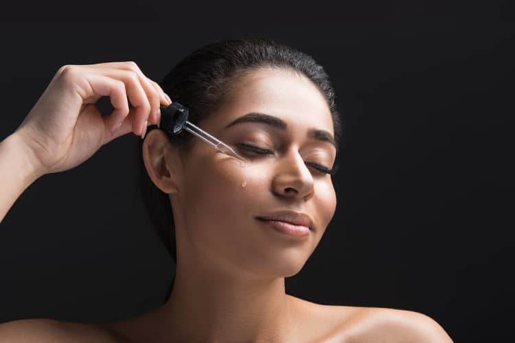 woman applying serum to her face