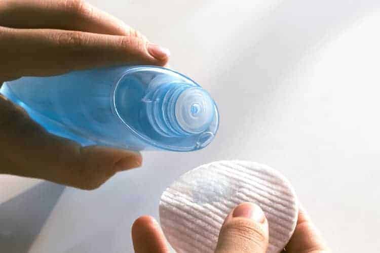 woman pouring micellar water onto cotton pad