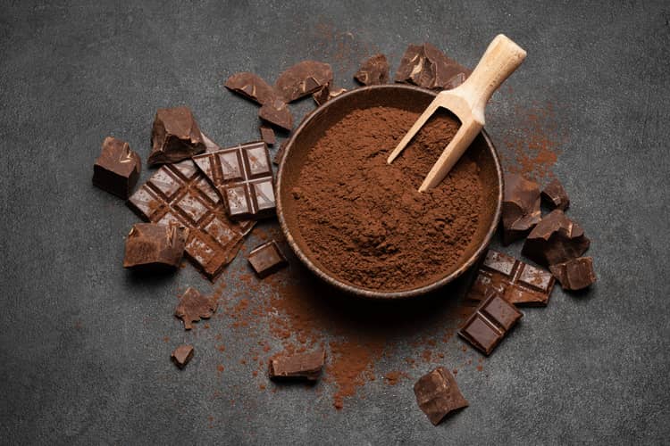 bowl of cacao powder surrounded by dark chocolate squares