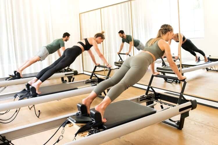 group doing pilates exercise on a reformer machine