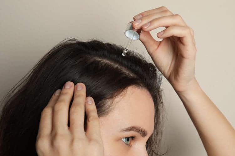 woman applying hair oil to her scalp